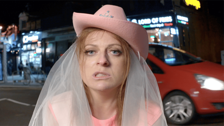 Blonde woman in a pink bridal cowboy hat making faces at the camera