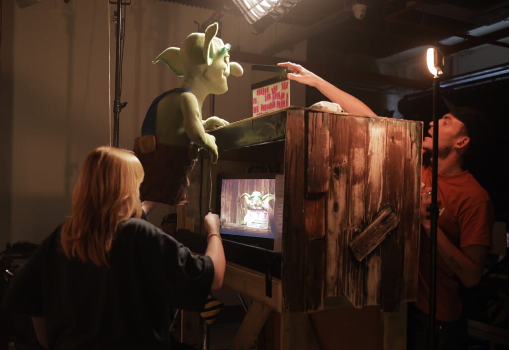 Puppeteer looks at monitor as she operates puppet